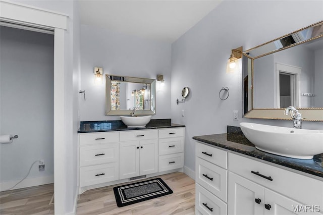 bathroom with two vanities, wood finished floors, and baseboards