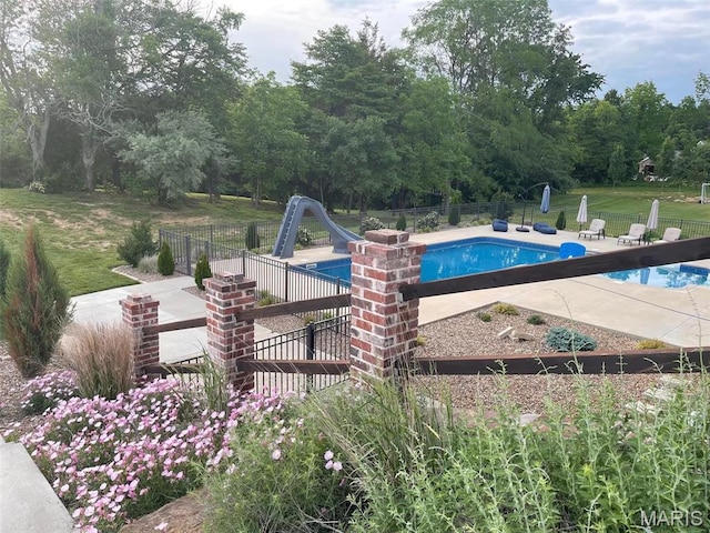 view of swimming pool with a water slide and a patio