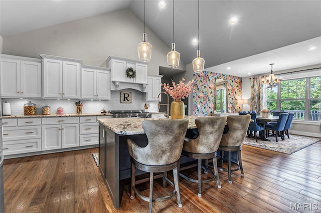 165 Kingsborough Ct, Jackson, MO 63755 - kitchen with high vaulted ceiling, a chandelier, a center island with sink, dark wood finished floors, and light stone countertops