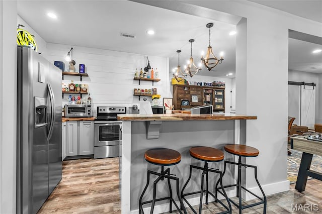 165 Kingsborough Ct, Jackson, MO 63755 - kitchen with appliances with stainless steel finishes, open shelves, a kitchen breakfast bar, a barn door, and light wood-type flooring