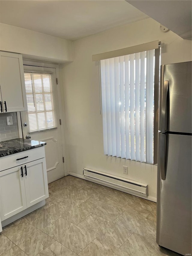 kitchen with freestanding refrigerator, a baseboard heating unit, white cabinets, and dark stone counters