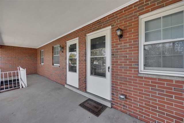 entrance to property featuring a porch and brick siding
