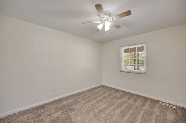 carpeted spare room with baseboards and a ceiling fan