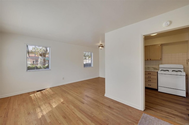 empty room with a smoke detector, light wood-style floors, and baseboards