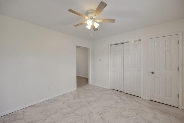 unfurnished bedroom with light marble finish flooring, a closet, baseboards, and ceiling fan