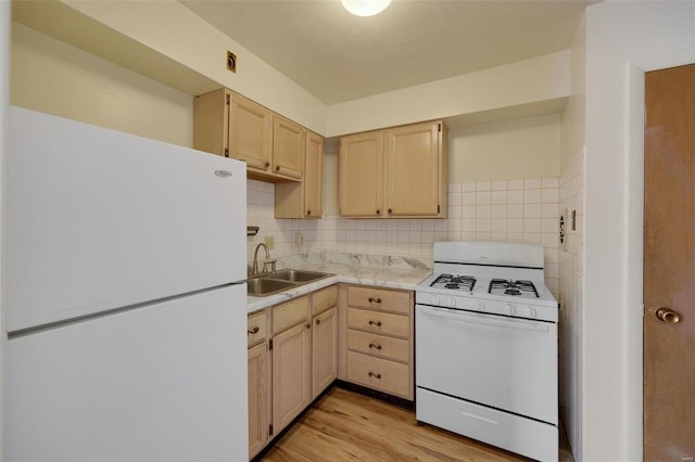 kitchen featuring white appliances, light brown cabinets, a sink, light countertops, and light wood finished floors