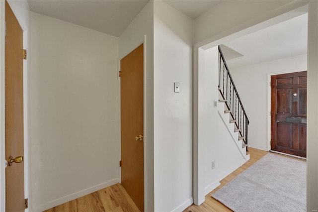 foyer with light wood-style flooring, stairway, and baseboards