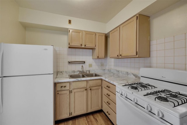 kitchen with white appliances, a sink, light brown cabinets, light countertops, and light wood-style flooring