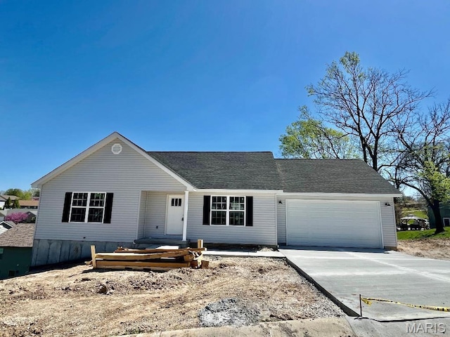 view of front of property featuring an attached garage, driveway, and a shingled roof