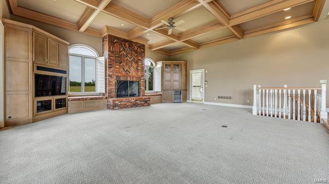 962 Hwy W, Foristell, MO 63348 - unfurnished living room with a fireplace, a ceiling fan, beamed ceiling, coffered ceiling, and carpet