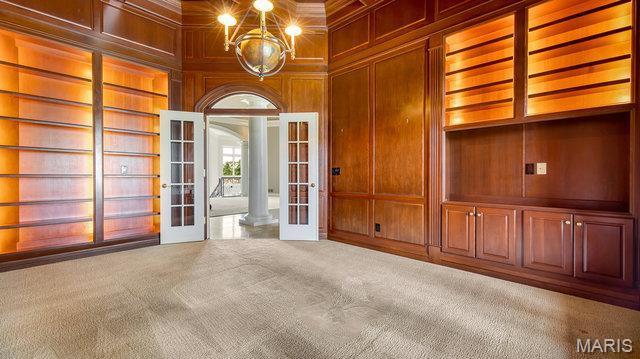 962 Hwy W, Foristell, MO 63348 - unfurnished room featuring french doors, built in shelves, wood walls, carpet flooring, and decorative columns