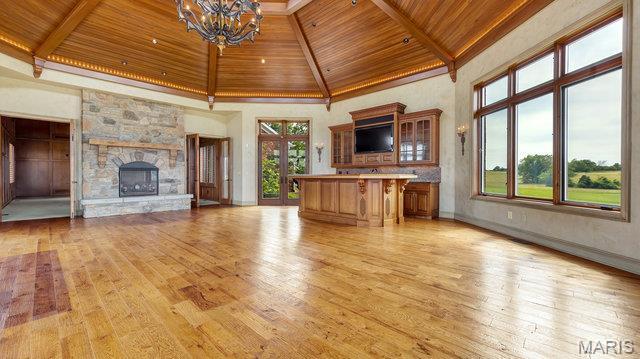 962 Hwy W, Foristell, MO 63348 - unfurnished living room featuring a wood ceiling with exposed beams, light wood finished floors, a chandelier, high vaulted ceiling, and a stone fireplace