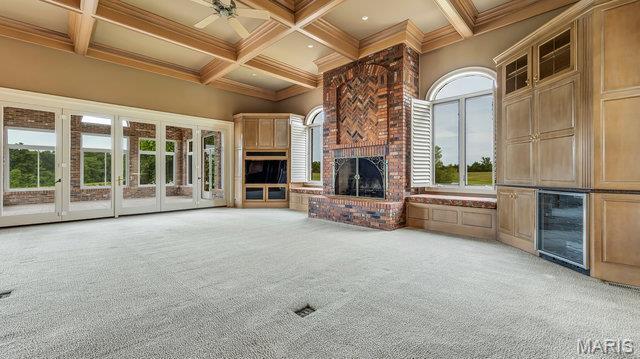 962 Hwy W, Foristell, MO 63348 - unfurnished living room featuring light colored carpet, a brick fireplace, coffered ceiling, beamed ceiling, and a ceiling fan