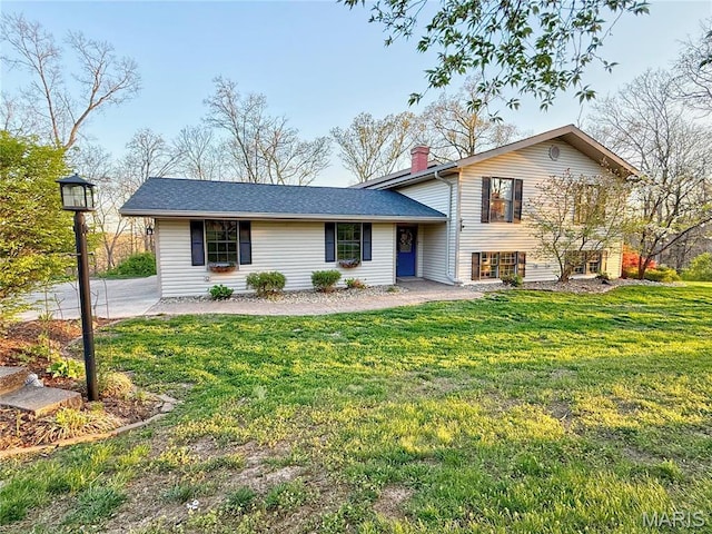 split level home with a chimney and a front lawn
