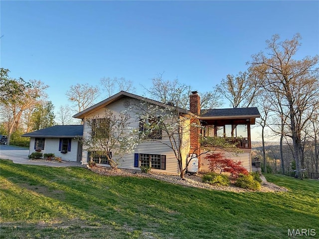 rear view of property featuring a chimney and a lawn