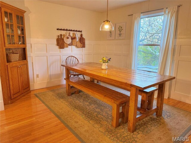 dining room featuring light wood-style flooring, a wainscoted wall, and a decorative wall