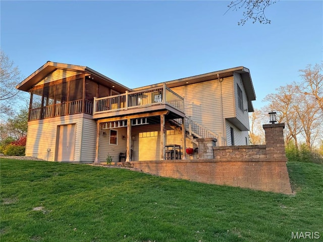back of property with a yard, a deck, stairs, and a sunroom