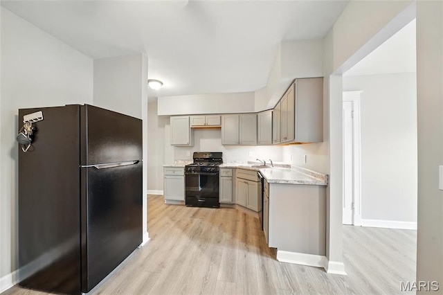 kitchen featuring black appliances, light wood-style flooring, gray cabinets, and baseboards