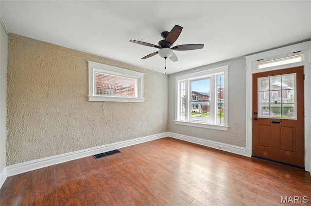 foyer entrance featuring a textured wall, baseboards, wood finished floors, and a ceiling fan