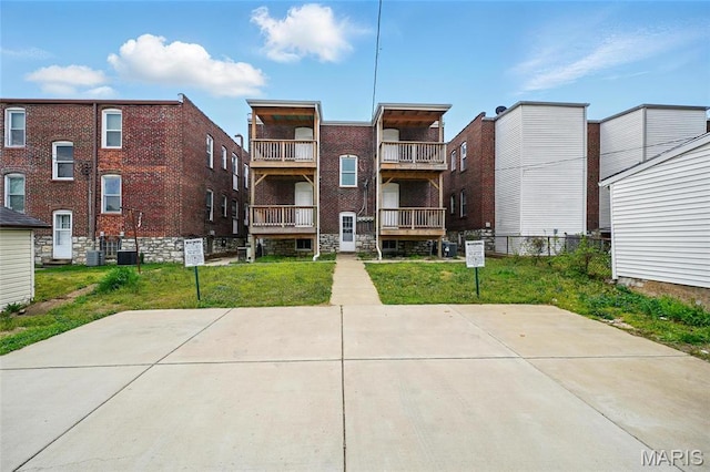 rear view of house featuring central AC unit and a yard