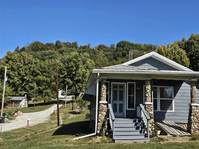 174 Clinton St, Hamburg, IL 62045 - view of front of property featuring stone siding, a front yard, covered porch, a standing seam roof, and metal roof