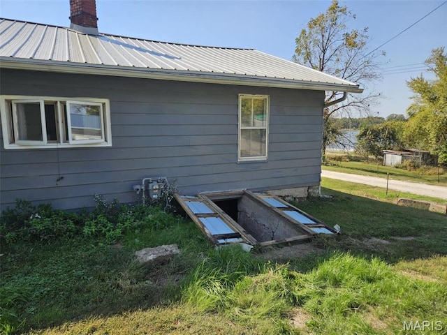 174 Clinton St, Hamburg, IL 62045 - exterior view of gutters, a metal roof, a downspout, a chimney, and a bulkhead entry
