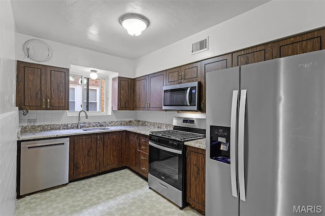 7273 Dartmouth Ave, Saint Louis, MO 63130 - kitchen featuring stainless steel appliances, a sink, light flooring, dark brown cabinets, and light stone counters