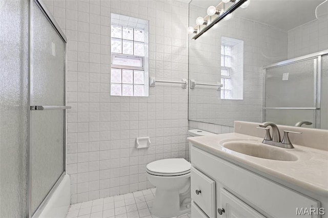 7273 Dartmouth Ave, Saint Louis, MO 63130 - full bathroom featuring tile walls, tile patterned floors, vanity, toilet, and enclosed tub / shower combo