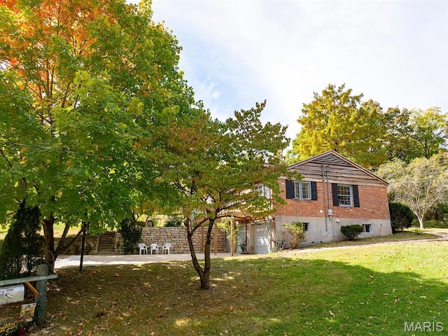 view of side of property with a lawn, an attached garage, and brick siding