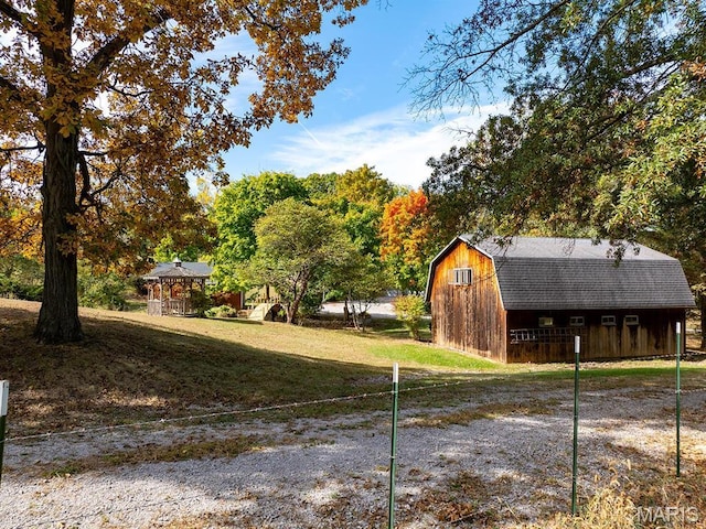 view of property exterior featuring a gambrel roof, an outdoor structure, and a yard