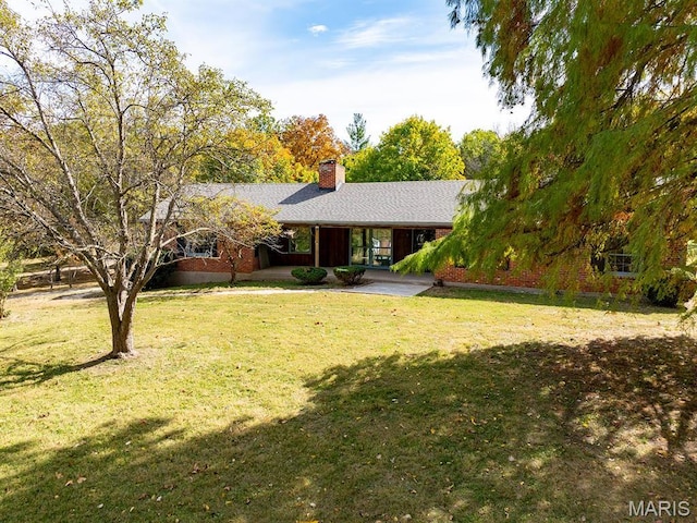 ranch-style house featuring a chimney and a front yard