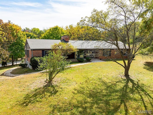 ranch-style home featuring brick siding, a front lawn, and a chimney