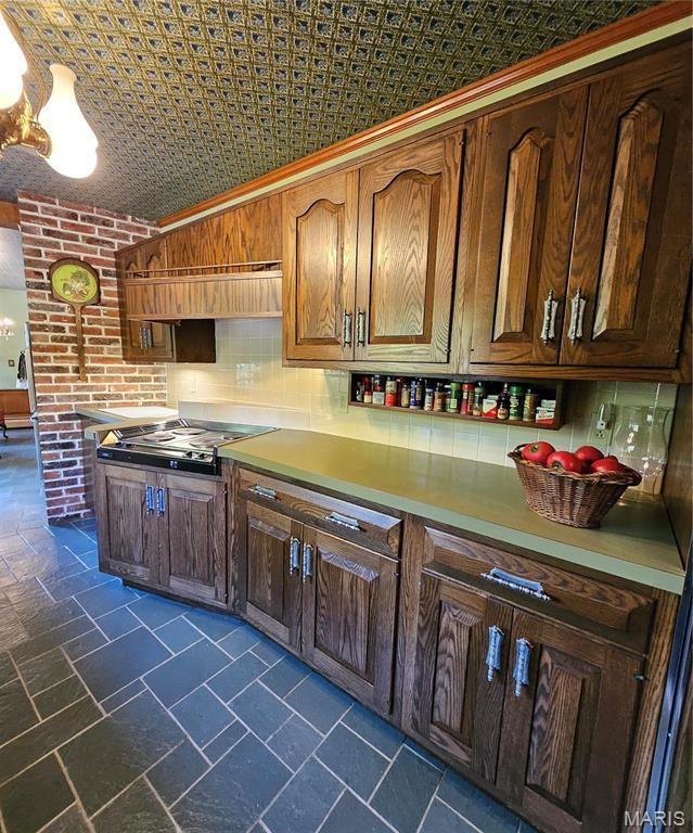 kitchen with an ornate ceiling, cooktop, light countertops, and backsplash