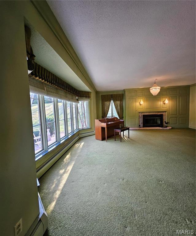 carpeted living room featuring a textured ceiling, a brick fireplace, and a baseboard heating unit