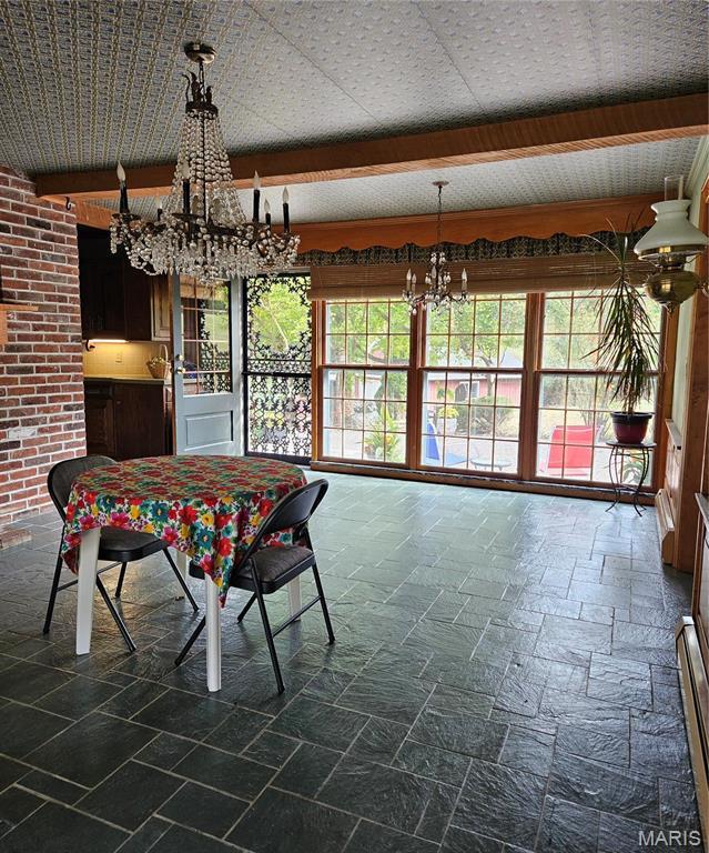 dining space with a chandelier and stone tile flooring