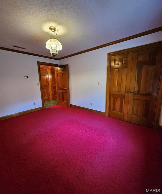 spare room with baseboards, ornamental molding, carpet flooring, and a textured ceiling
