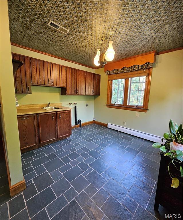 laundry area with cabinet space, a baseboard heating unit, electric dryer hookup, a chandelier, and baseboards