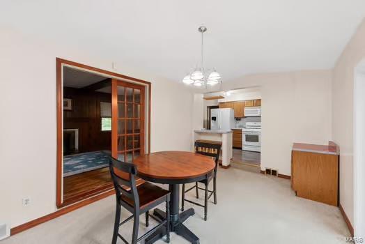 1627 Monticello Dr, Saint Louis, MO 63138 - dining room with baseboards, a chandelier, and light carpet