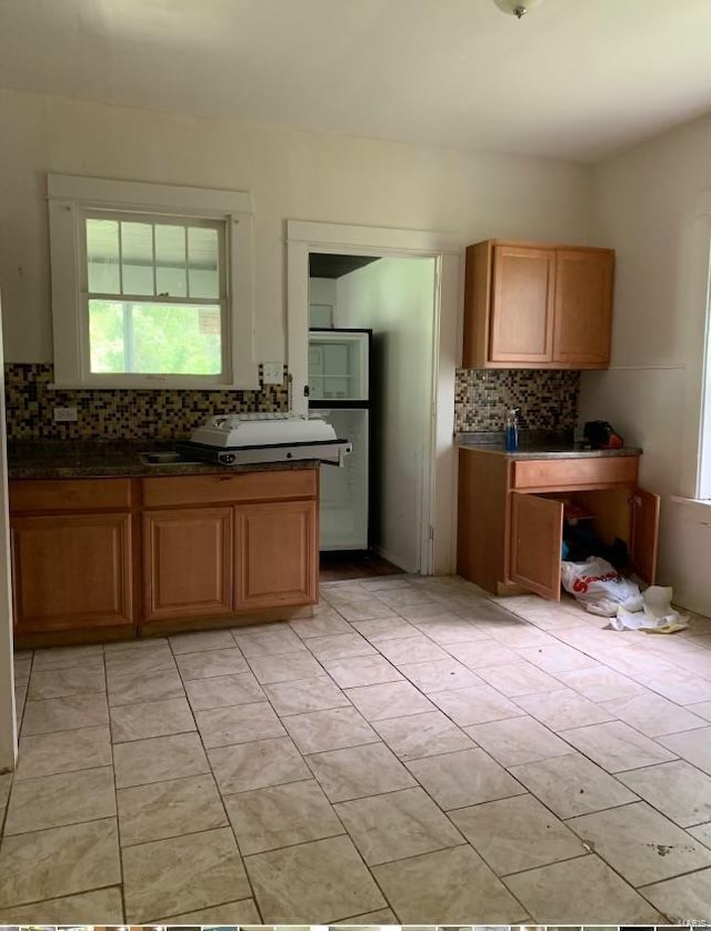 12540 Bellefontaine Rd, Saint Louis, MO 63138 - kitchen featuring tasteful backsplash, healthy amount of natural light, light tile patterned floors, and dark countertops