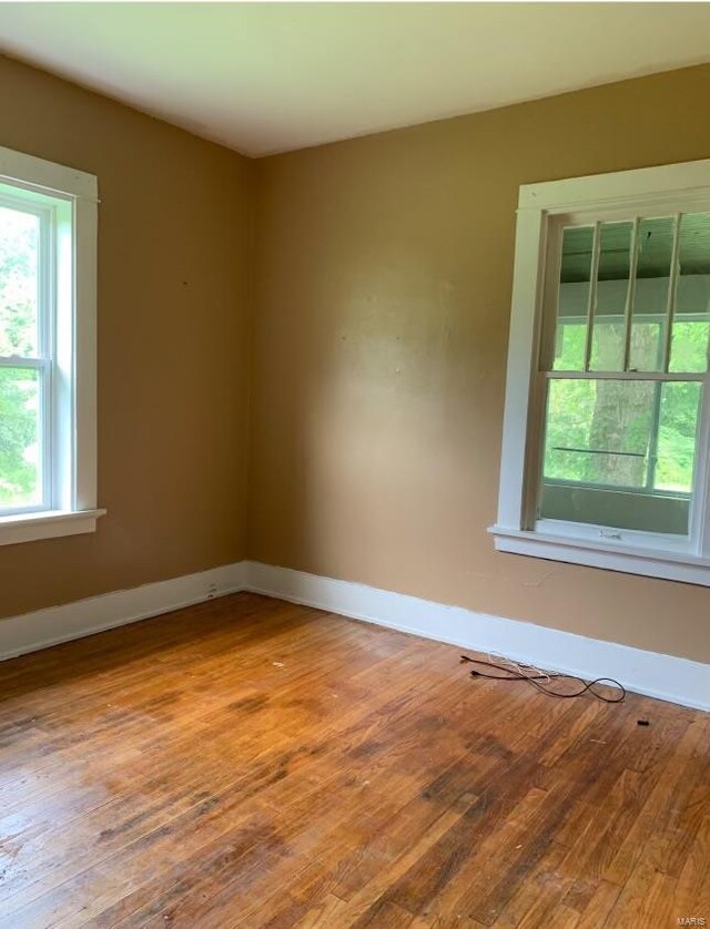 12540 Bellefontaine Rd, Saint Louis, MO 63138 - empty room featuring wood finished floors, plenty of natural light, and baseboards