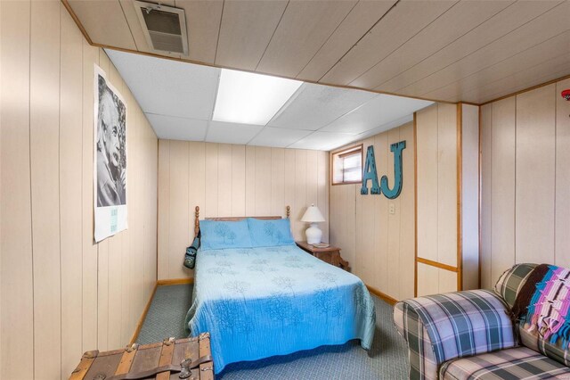 bedroom with carpet floors, baseboards, and wood walls