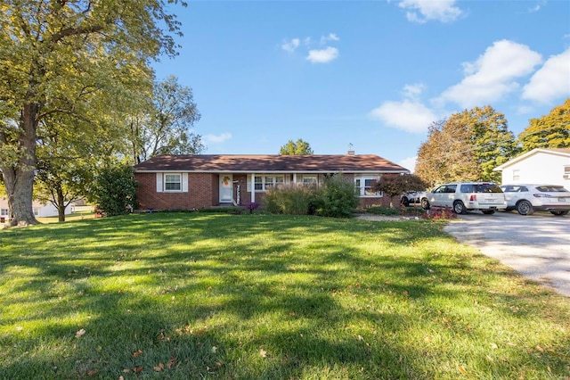 ranch-style house with a front lawn, driveway, and brick siding