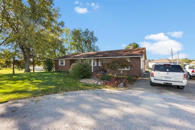 ranch-style house featuring brick siding, a front yard, and a chimney
