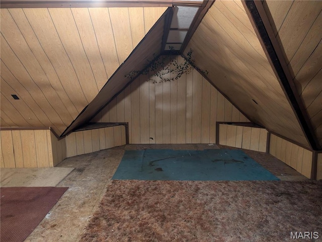bonus room featuring vaulted ceiling and wood walls