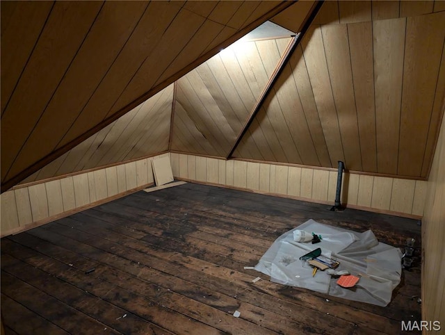 bonus room with dark wood-type flooring and wood walls