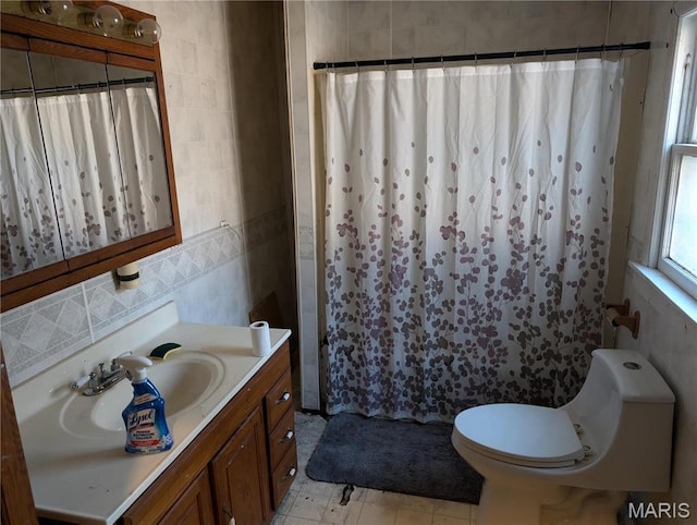 full bathroom featuring a shower with shower curtain, vanity, toilet, and tile walls
