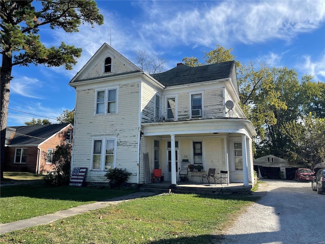 victorian home featuring covered porch, a front yard, and an outdoor structure