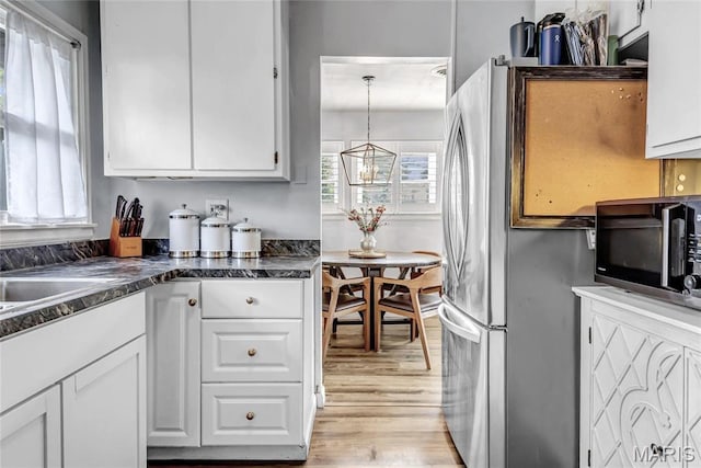 11409 Manchester Rd, Saint Louis, MO 63122 - kitchen featuring white cabinetry, light wood-type flooring, dark countertops, a chandelier, and freestanding refrigerator