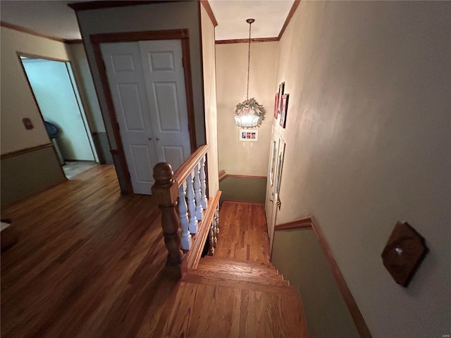 stairs with ornamental molding, wood finished floors, and baseboards