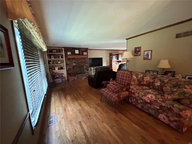 living room featuring wood finished floors, a fireplace, and built in features